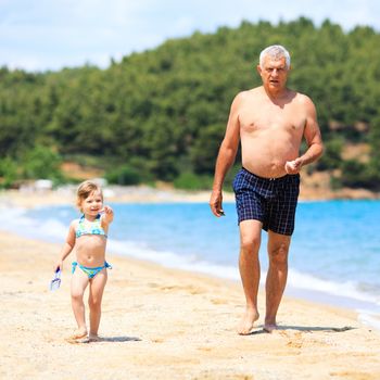 Senior man with granddaughter walking on the beautiful tropical beach