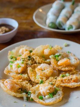 Banh Khot with shrimps, miniature fried pancakes served in Vietnam. Goi cuon, Vietnamese spring rolls, in the background. Very shallow depth of field with the first pancake in focus