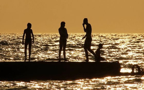 people silhouettes on the sea at sunset Family resting group of people summer vacation