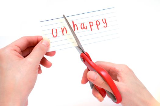 Female using scissors to remove the word unhappy to read happy concept for self belief, positive attitude and motivation