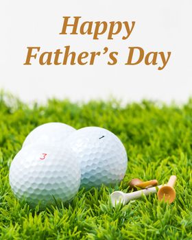 Three white golf balls and tees with a Fathers Day inscription.