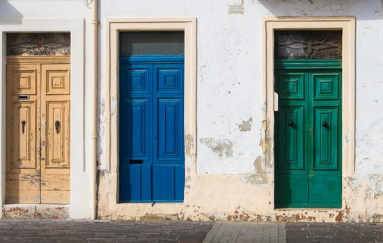 In the rays of morning sunlight, 3 similar doors, different in the color. House at the island Malta, Europe.