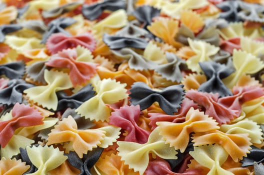 Background multi-colored pasta in the shape of bows are on the surface, textured