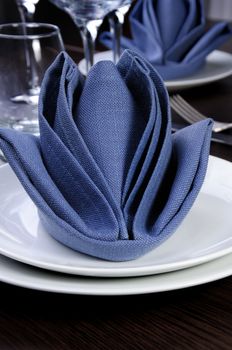 Folded textile cloth in the form of flower bud on a plate