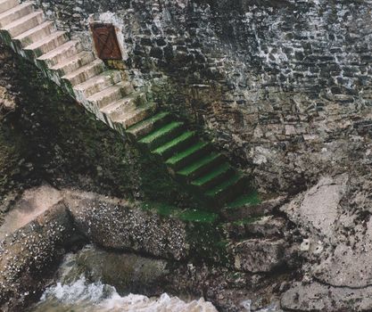 Concrete stairs against a stone wall leading to sea level