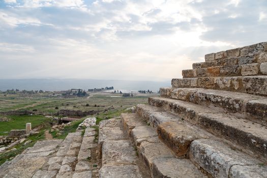 View of Hyerapolis Ancient City with stone ruins on cloudy sky background.