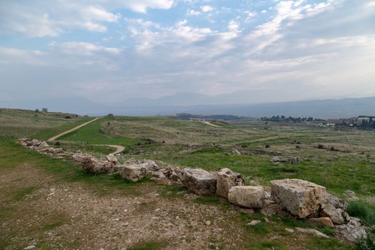 View of Hyerapolis Ancient City with stone ruins on cloudy sky background.