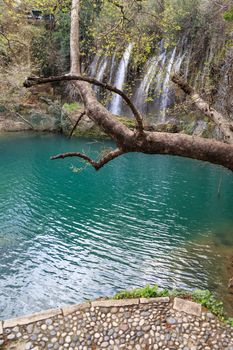 View of Kursunlu Waterfall in Antalya, flowing from high, with green trees and plants around.