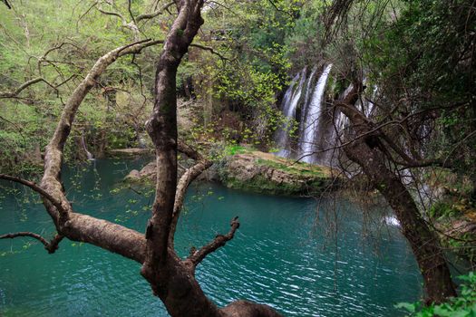 View of Kursunlu Waterfall in Antalya, flowing from high, with green trees and plants around.