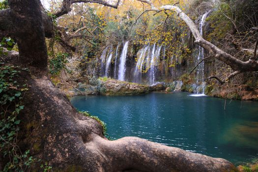 View of Kursunlu Waterfall in Antalya, flowing from high, with green trees and plants around.
