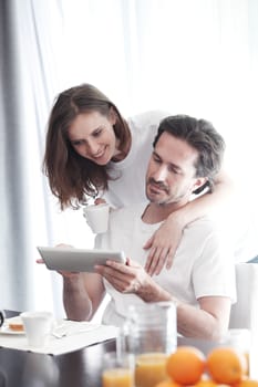 Couple having breakfast at home and using tablet