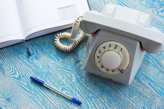 The photo depicts a landline phone with a notebook