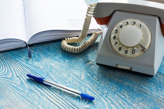 The photo depicts a landline phone with a notebook