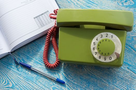 The photo depicts a landline phone with a notebook