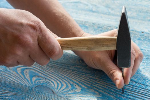 The photo shows the hand hammer a nail