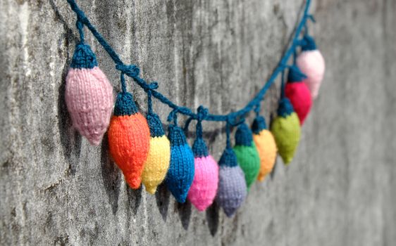 Group of colorful Xmas ornament for winter holiday, handmade product, knitted Christmas lights bulb on old wall background