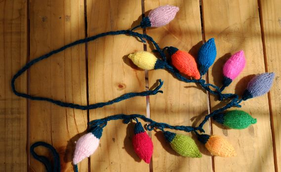 Group of colorful Xmas ornament for winter holiday, handmade product, knitted Christmas lights bulb on wood background