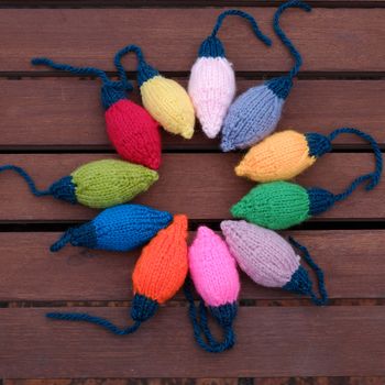 Group of colorful Xmas ornament for winter holiday, handmade product, knitted Christmas lights bulb on wood background