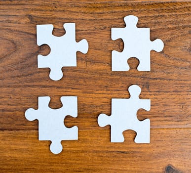 Four blue pieces of puzzle on wooden background