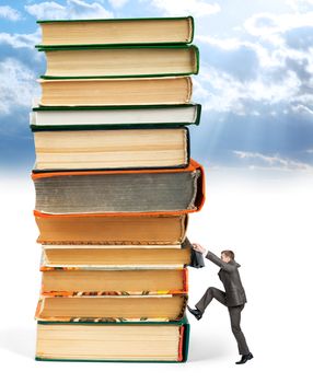 Pile of books with businessman climbing it on blue sky background