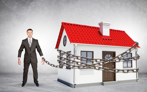 Businessman chained to house on grey background