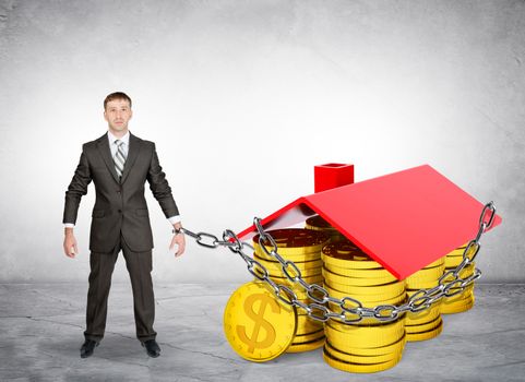 Businessman chained to house with coins on grey background