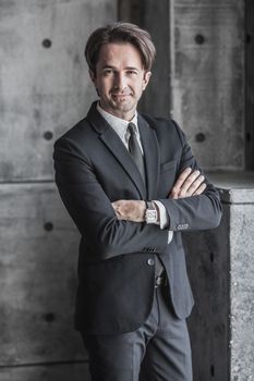Portrait of smiling businessman in suit over concrete wall background