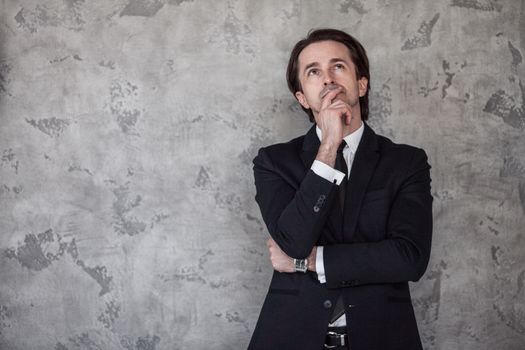 Portrait of businessman thinking against a concrete wall