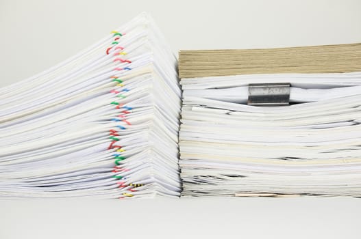 Overload paperwork of report and receipt with colorful paperclip have blur brown envelope on document with white background.