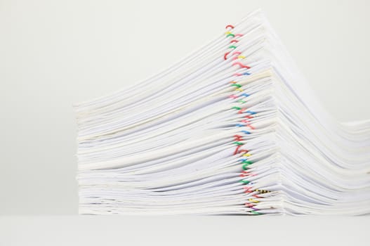 Overload paper of report and receipt with colorful paperclip on white background.