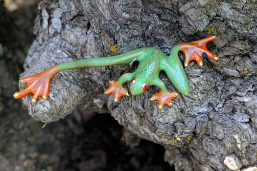 This ornamental green frog statue with orange feet is decorated with tiny small black spots.