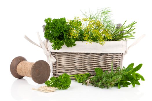 sage, parsley and rosemary in wicker basket, on a white background
