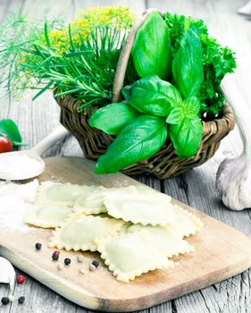 Homemade pasta ravioli with fresh basil, on wooden background