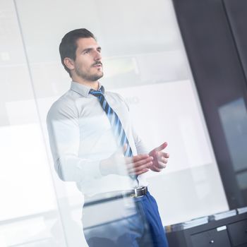 Business man making a presentation in front of whiteboard. View through glass.