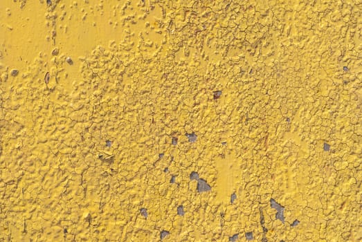 fragment of an iron surface is covered with yellow color paint, which has long been under the influence of different climatic conditions