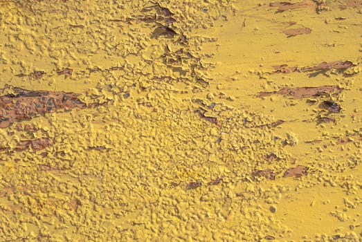 fragment of an iron surface is covered with yellow color paint, which has long been under the influence of different climatic conditions