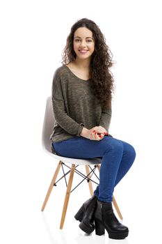 Beautiful woman sitting on a chair and smiling, isolated over white background 