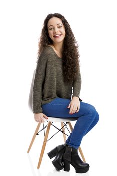 Beautiful woman sitting on a chair and smiling, isolated over white background 