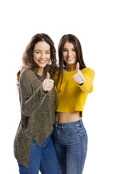 Studio portrait of two beautiful girls with thumbs up