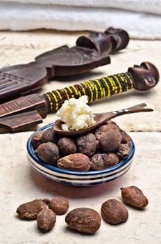 Shea nuts in a dish with a wooden spoon of shea butter