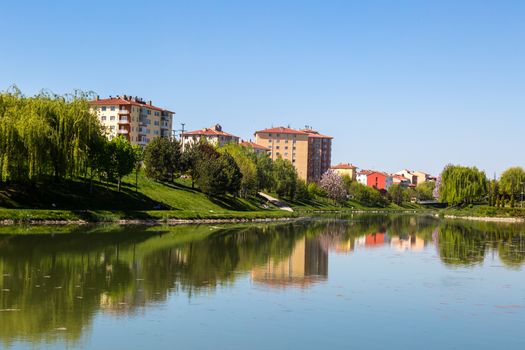 Landscape view of Porsuk River along Eskisehir with meadow area around, on bright blue sky background.