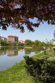 Landscape view of Porsuk River along Eskisehir with meadow area around, on bright blue sky background.