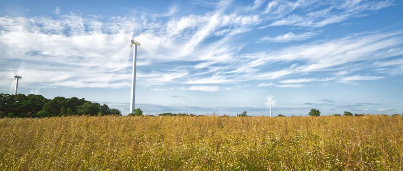 Wind Power Stations in Field with a partly cloudy sky.