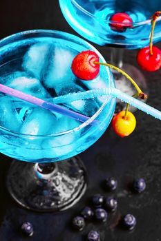glass of blue alcohol cocktail in glass with cherry