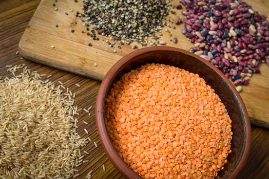 Lentils, red beans and brown rice on a wooden table and board