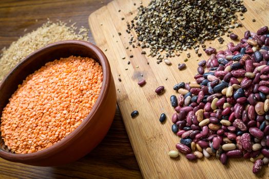 Lentils, red beans and brown rice on a wooden table and board