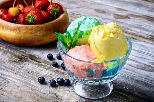 Bowl with fruit ice cream scattered on background of blueberries