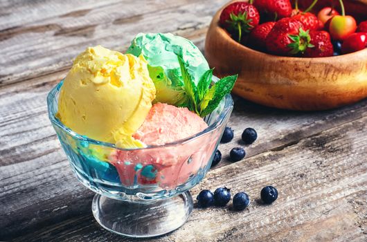 Bowl with fruit ice cream scattered on background of blueberries