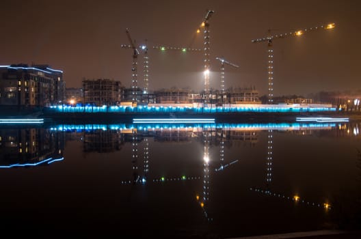 Tower cranes night view from the embankment of Admiral Lazarev, building in St. Petersburg