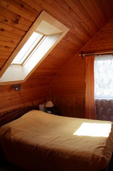 Bedroom interior in house attic with nice window in roof